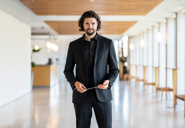 Man som håller i en dirigentpinne. Fotografi.