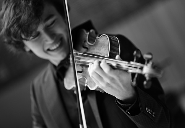 Ung man spelar fiol. Fotografi.