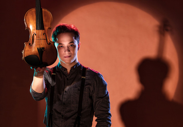 Ung man som håller i en violin. Fotografi