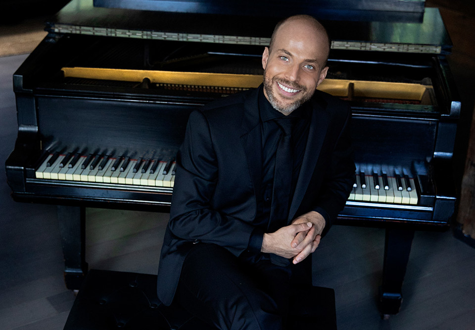 Man som sitter vid ett piano. Fotografi.