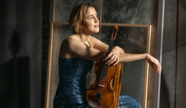 Kvinna som sitter med en violin. Fotografi.