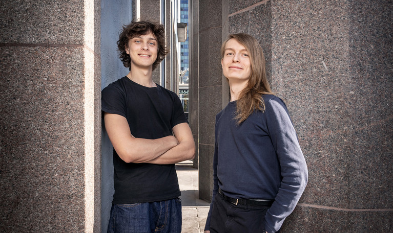 Two musicians leaning against a wall. Photo.